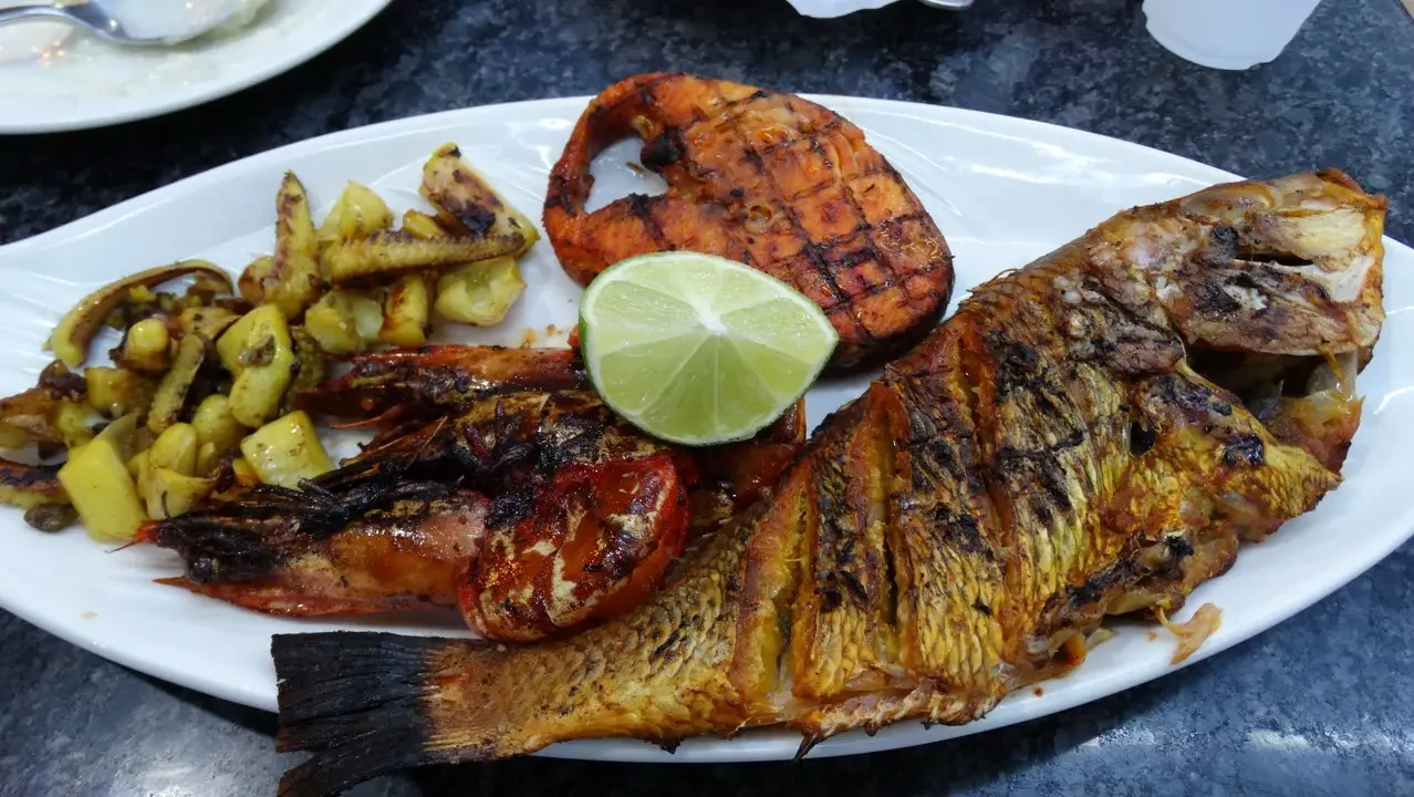 Pesce grigliato con accompagnamenti su un piatto.