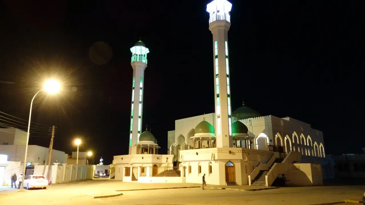 Vista notturna di una moschea con minareti in stile omanita.