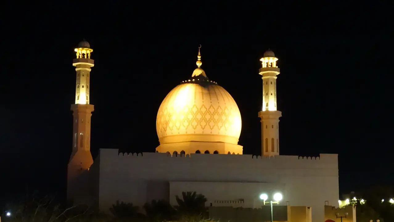 Vista notturna di una moschea con cupole dorate e minareti in Oman o Emirati Arabi Uniti.