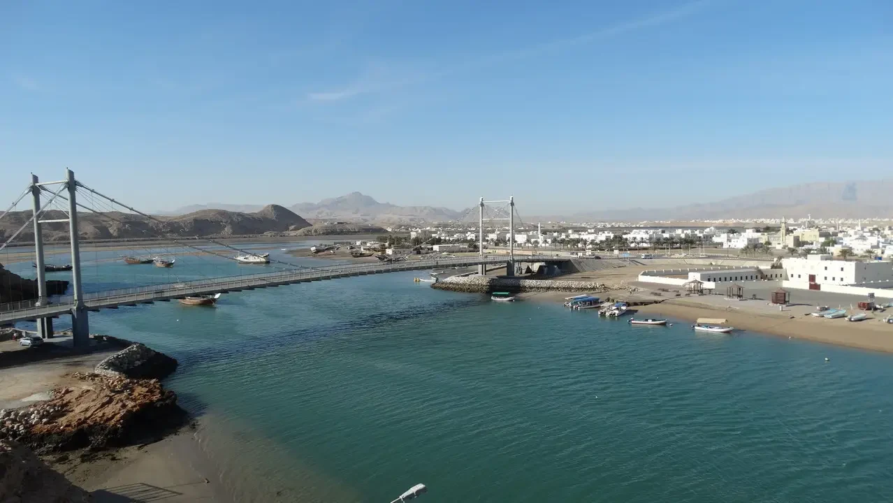 Un ponte si estende sull'acqua tra la terra e il mare in un paesaggio arido.