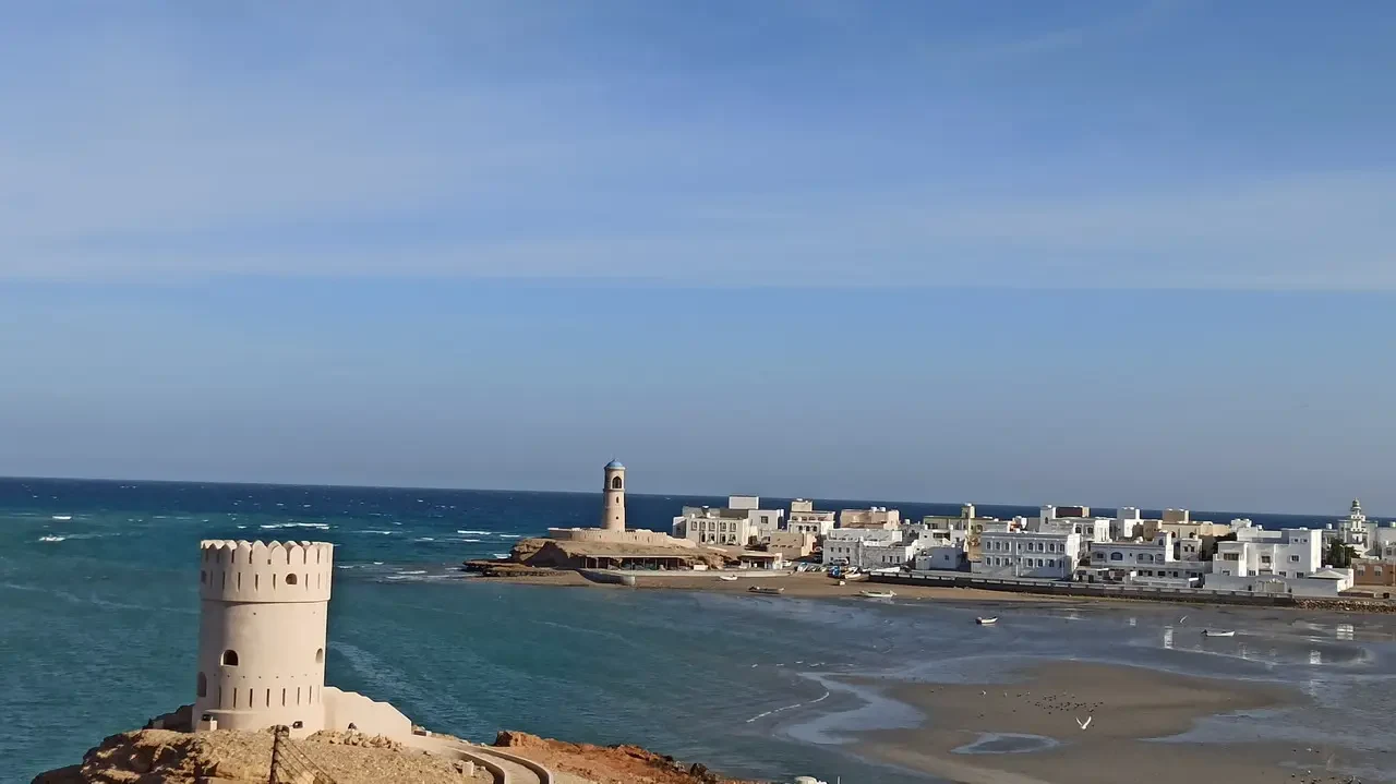 Una torre fortificata bianca domina il paesaggio costiero dell'Oman o degli Emirati Arabi Uniti.