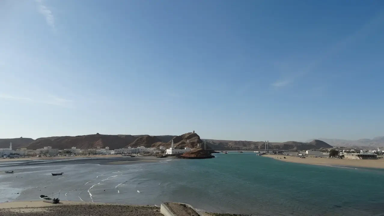 Vista costiera con spiaggia sabbiosa e acque turchesi sotto un cielo sereno.