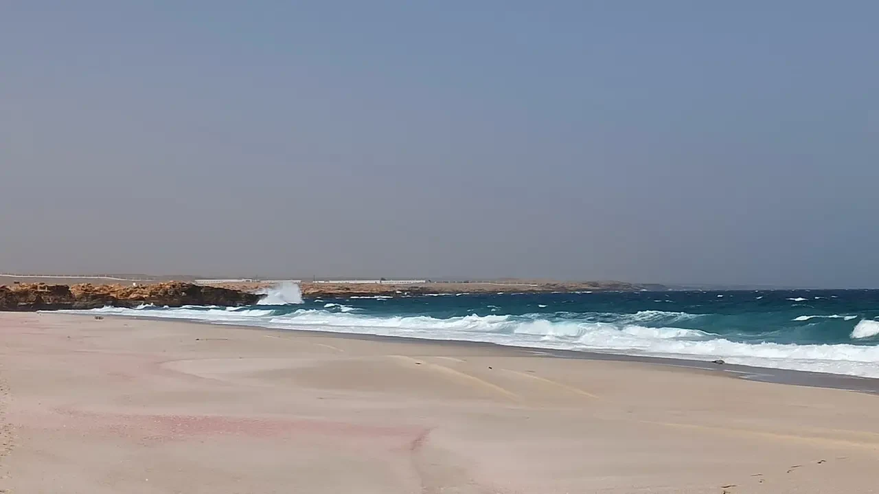 Onde blu si infrangono sulla spiaggia sabbiosa sotto il cielo aperto.