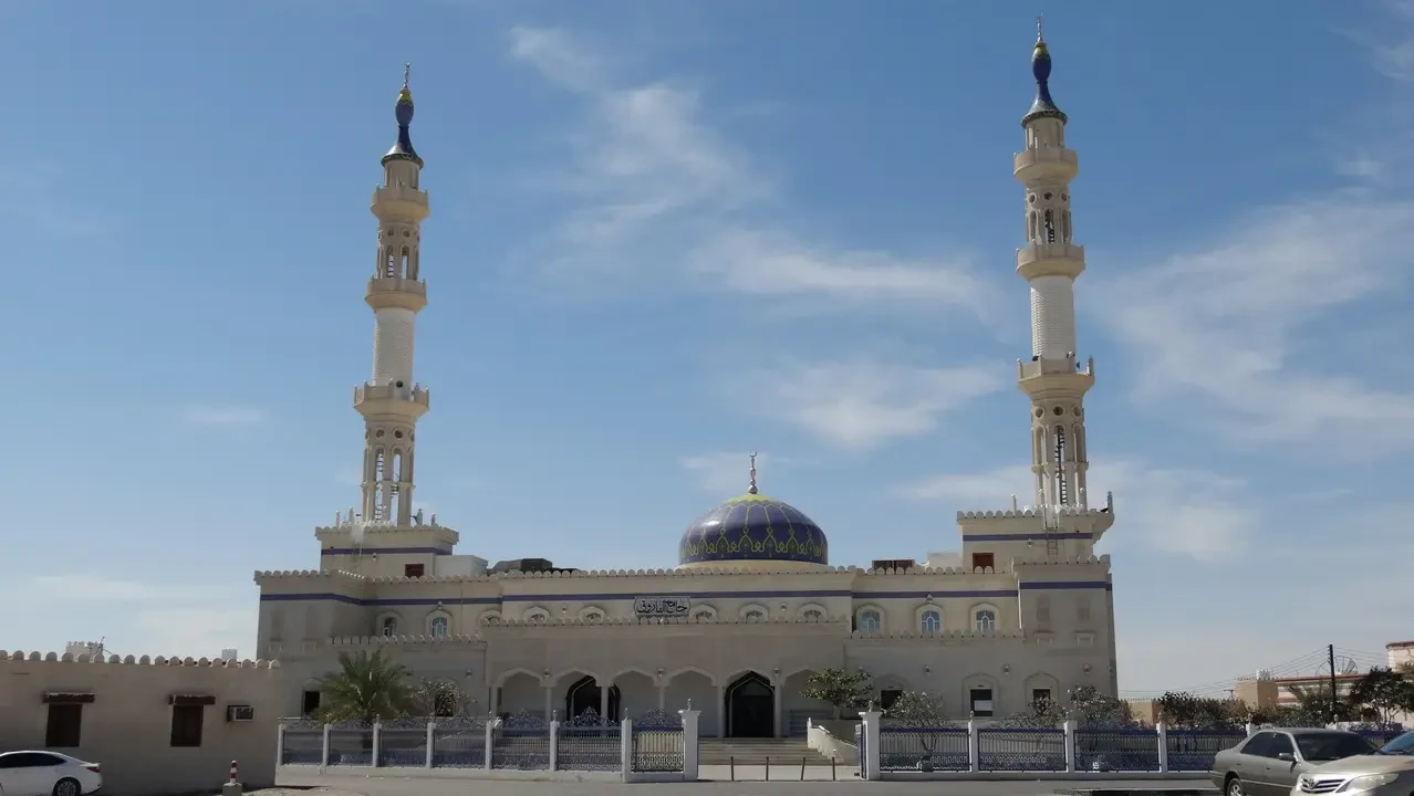 Una grande moschea con minareti si staglia sotto il cielo luminoso.