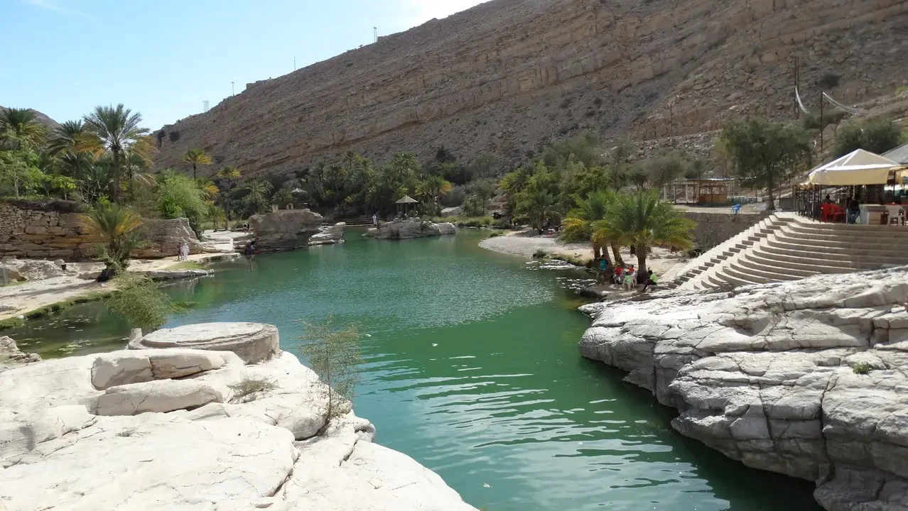 Un fiume turchese scorre attraverso un paesaggio roccioso in Oman.