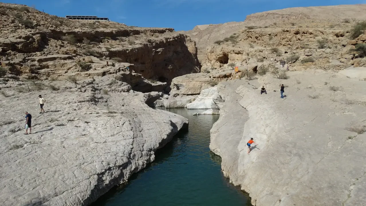 Un corso d'acqua turche blu scorre attraverso un canyon roccioso sotto il sole.