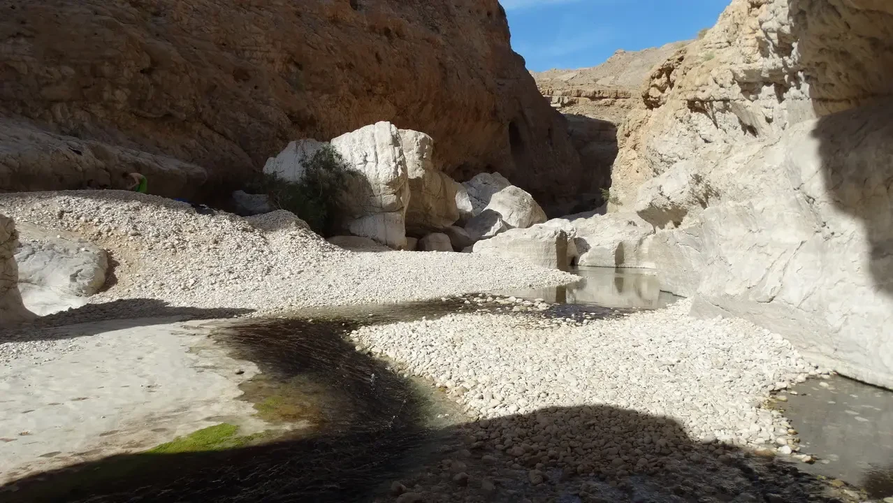 Un fiume scorre attraverso un letto di rocce rocciose nella regione del Wadi Bani Khalid in Oman.