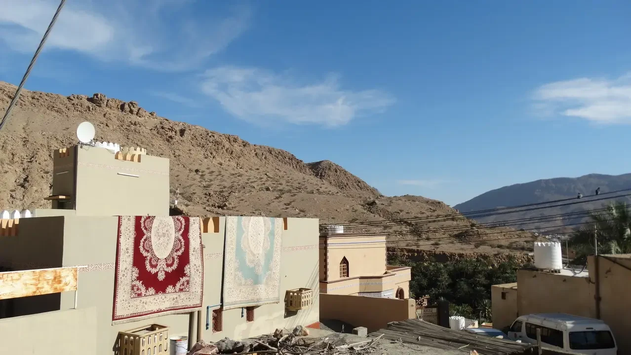 Caseggiati in pietra con decorazioni tradizionali si stagliano contro un paesaggio collinare arido.