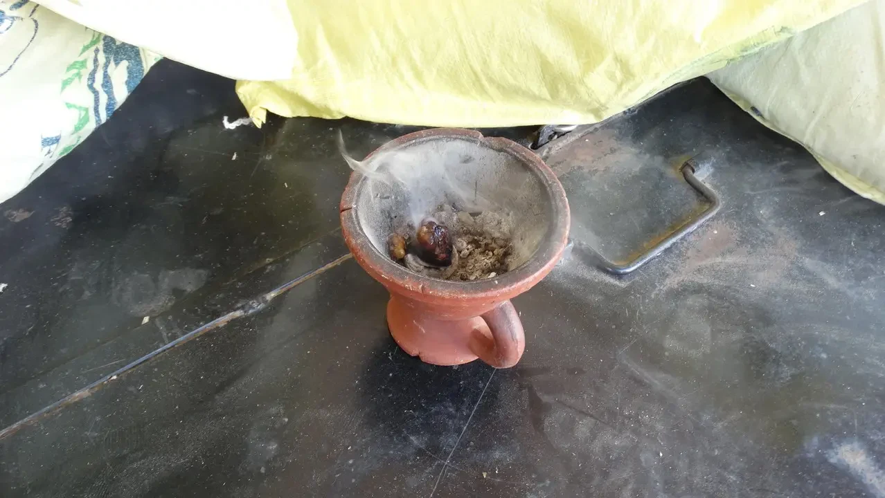 Una piccola pentola in terracotta è posizionata su una superficie scura con un tessuto giallo sopra di essa.