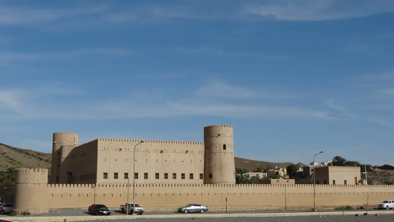 Una fortezza in terra cotta con mura lunghe si staglia sotto il cielo aperto.
