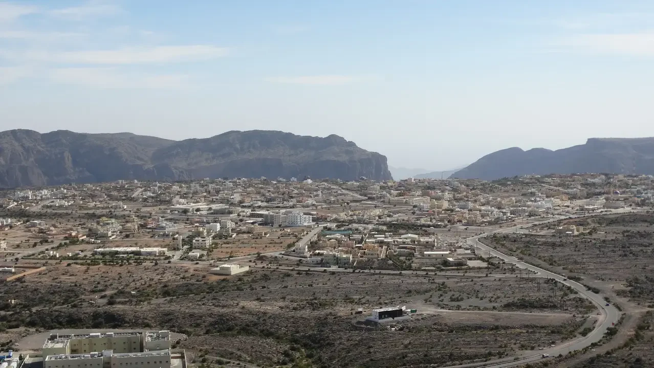 Paesaggio urbano e collinare con terreno arido in Oman o Emirati Arabi Uniti.