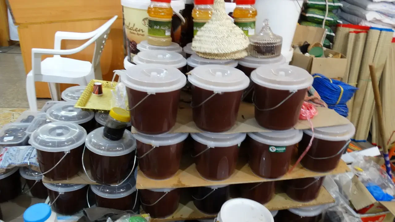 Contenitori marroni riempiti con materiale scuro sono disposti su scaffali di legno.