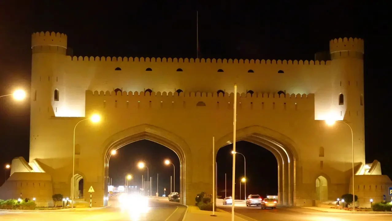 Fortezza illuminata di notte in stile arabo lungo una strada trafficata.