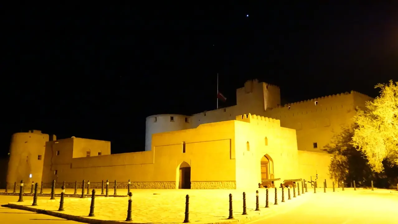 Mura di una fortezza illuminata di notte in Oman.