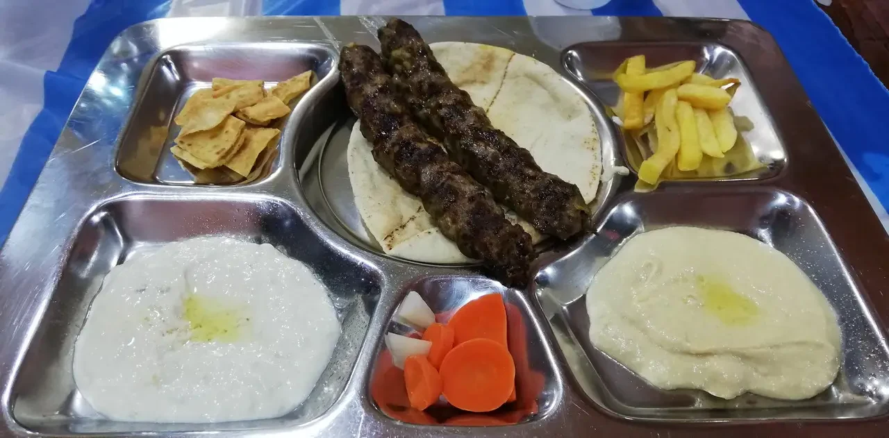 Un piatto di cibo tradizionale viene servito su un vassoio metallico.