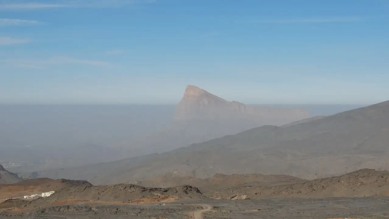 Paesaggio desertico con una formazione rocciosa prominente all'orizzonte.
