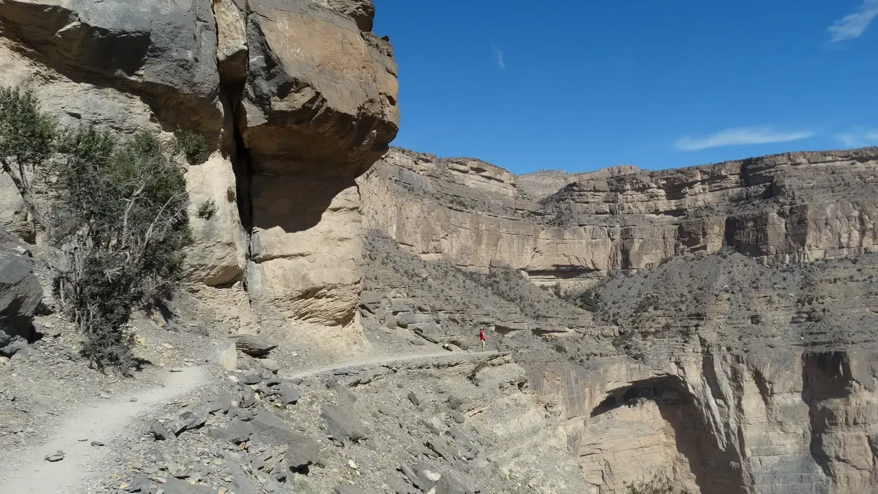 Paesaggio roccioso e desertico con una strada sterrata che attraversa la gola.