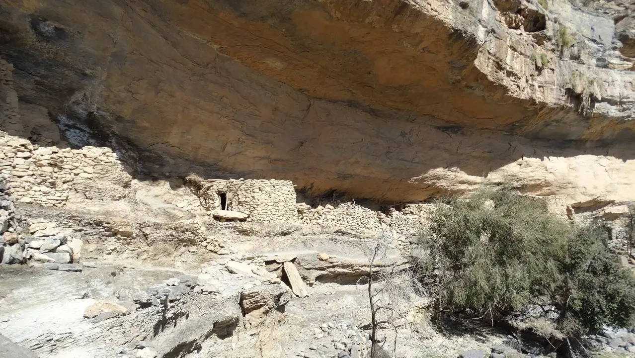 Formazione rocciosa arida con antiche costruzioni in pietra nel paesaggio desertico.