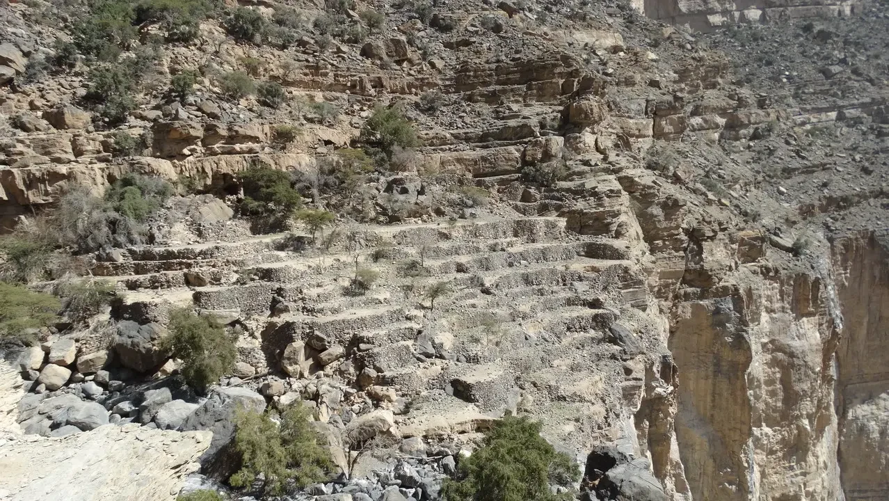 Struttura a gradoni scavata nella roccia lungo un fiume in Oman o Emirati Arabi Uniti.