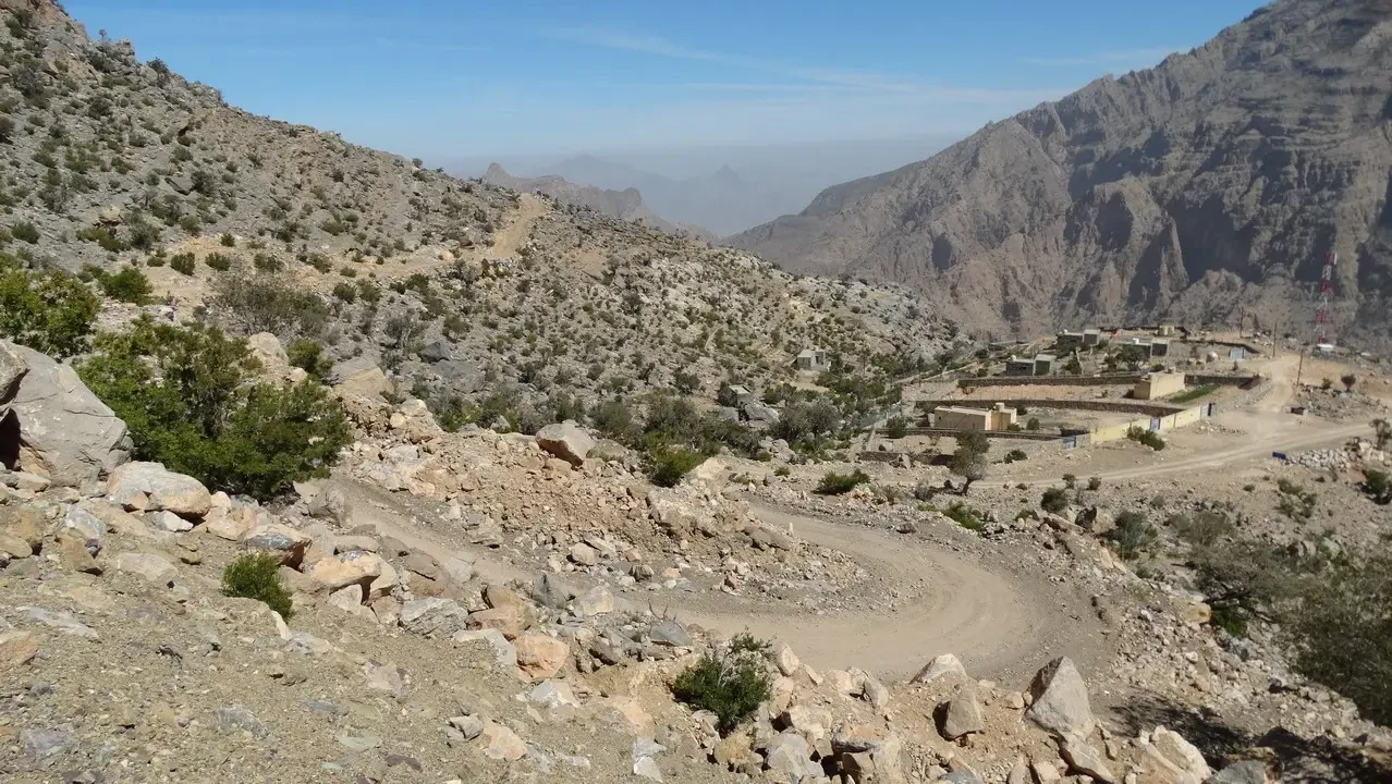 Paesaggio montano arido con un sentiero che attraversa una valle in Oman o Emirati Arabi Uniti.