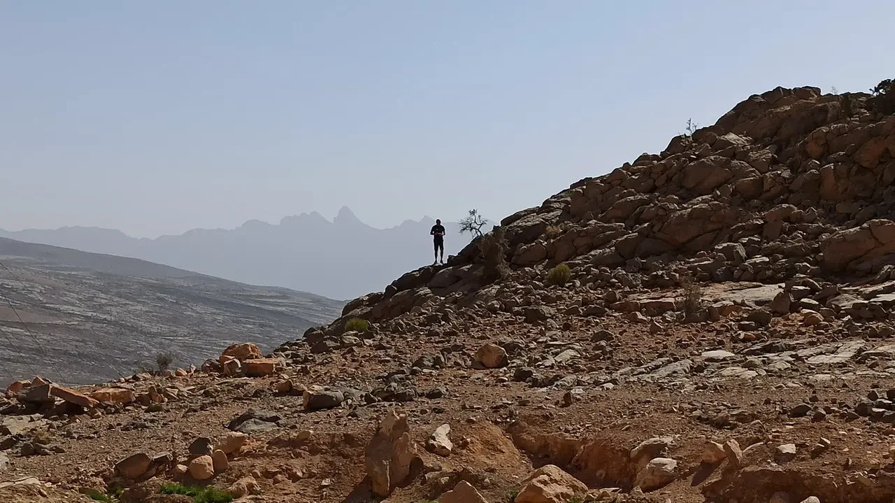 Una persona cammina su un pendio roccioso nel deserto.