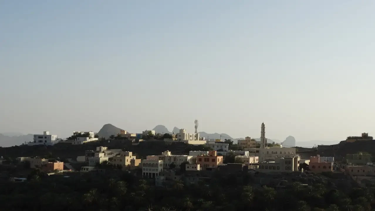 Panorama di un insediamento collinare con edifici in pietra sotto un cielo chiaro.