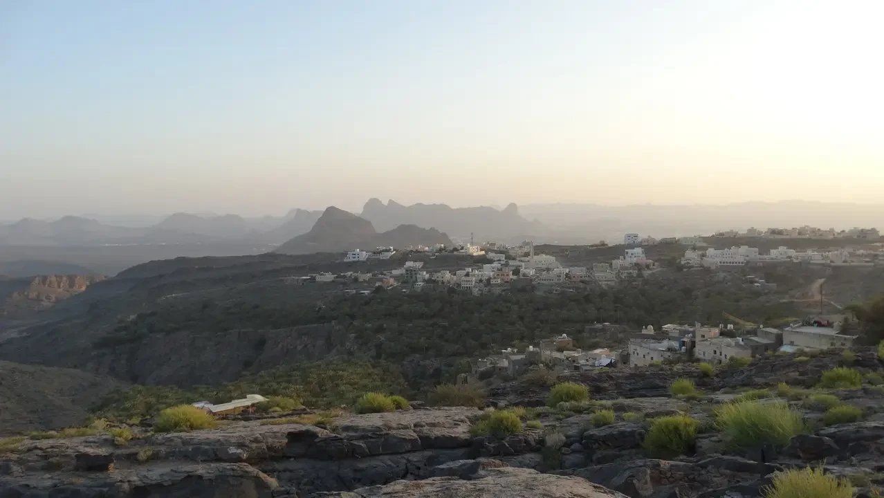 Tramonto spettacolare sulle colline desertiche di Oman o Emirati Arabi Uniti con abitazioni sparse.