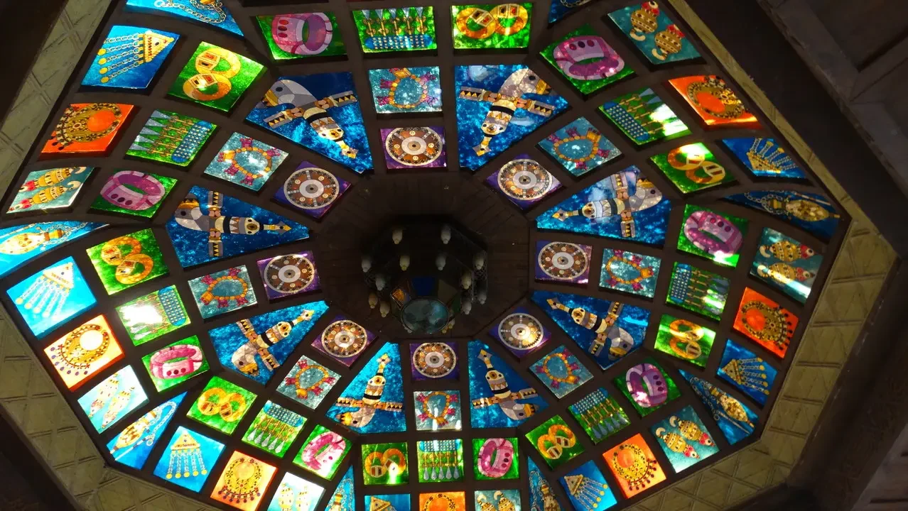 Mosaico decorativo di colori vivaci copre il soffitto architettonico interno.
