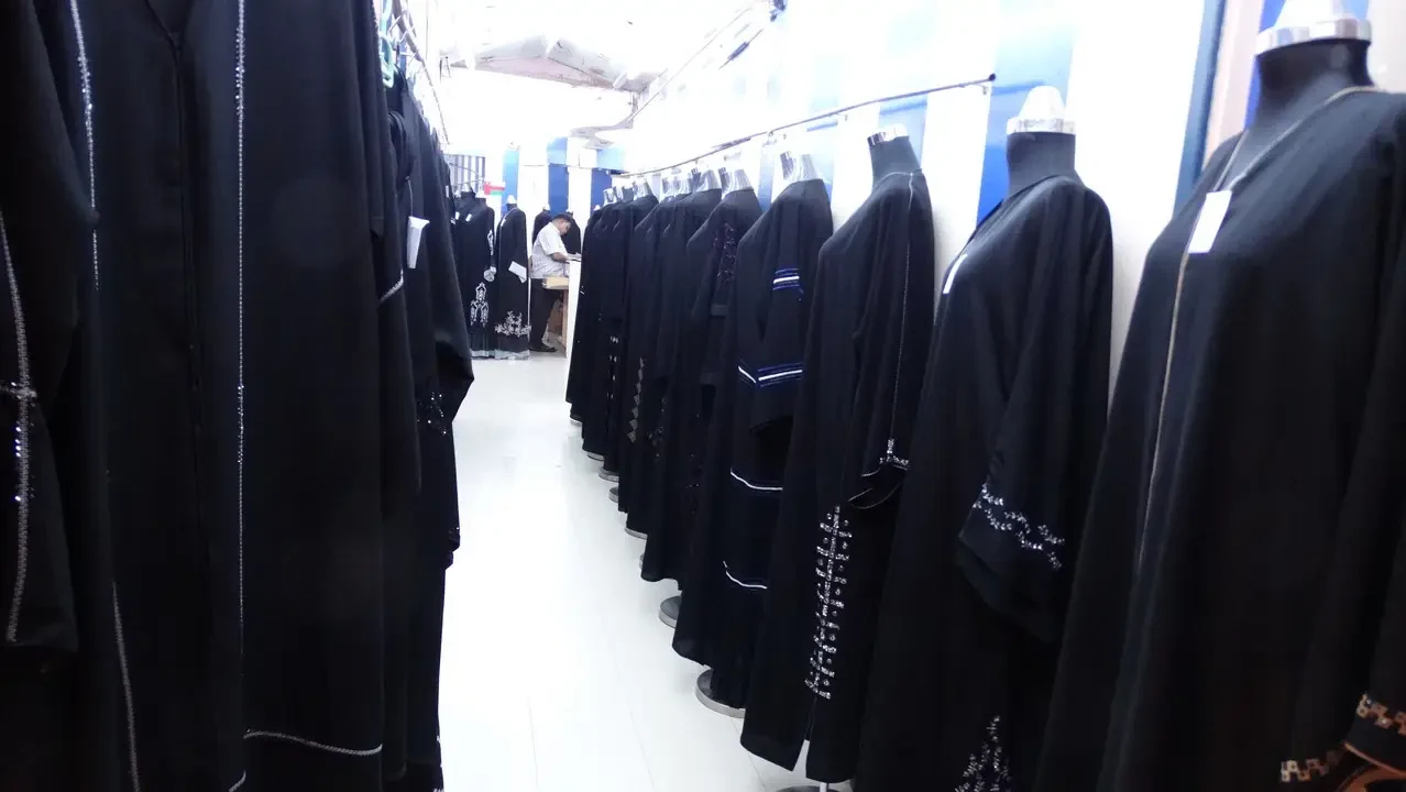 Una fila di abiti neri sono esposti in un negozio.