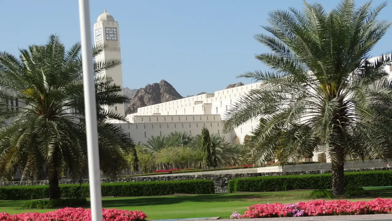 Vista panoramica di un complesso architettonico moderno circondato da vegetazione e montagne in Oman o negli Emirati Arabi Uniti.