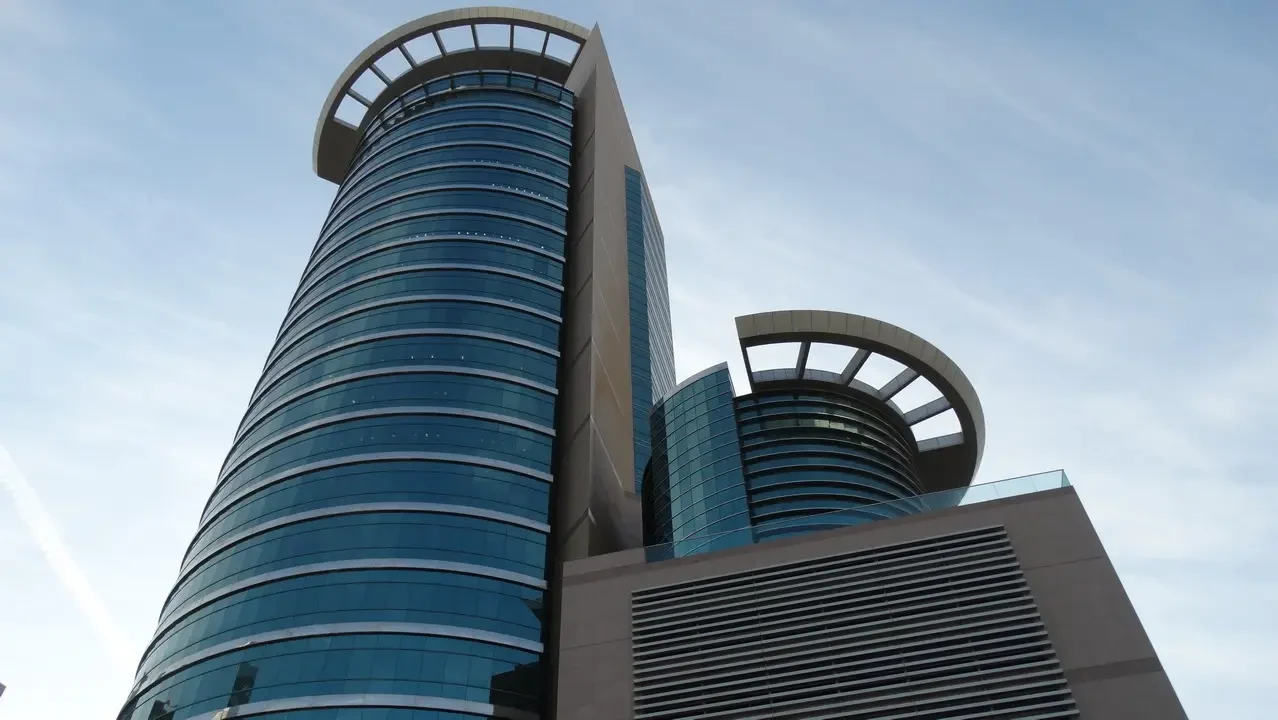 Edificio moderno con facciata di vetro sotto un cielo azzurro.