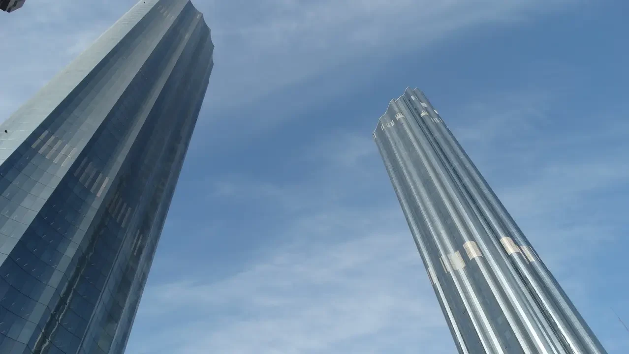 Due grattacieli moderni si stagliano contro il cielo azzurro.