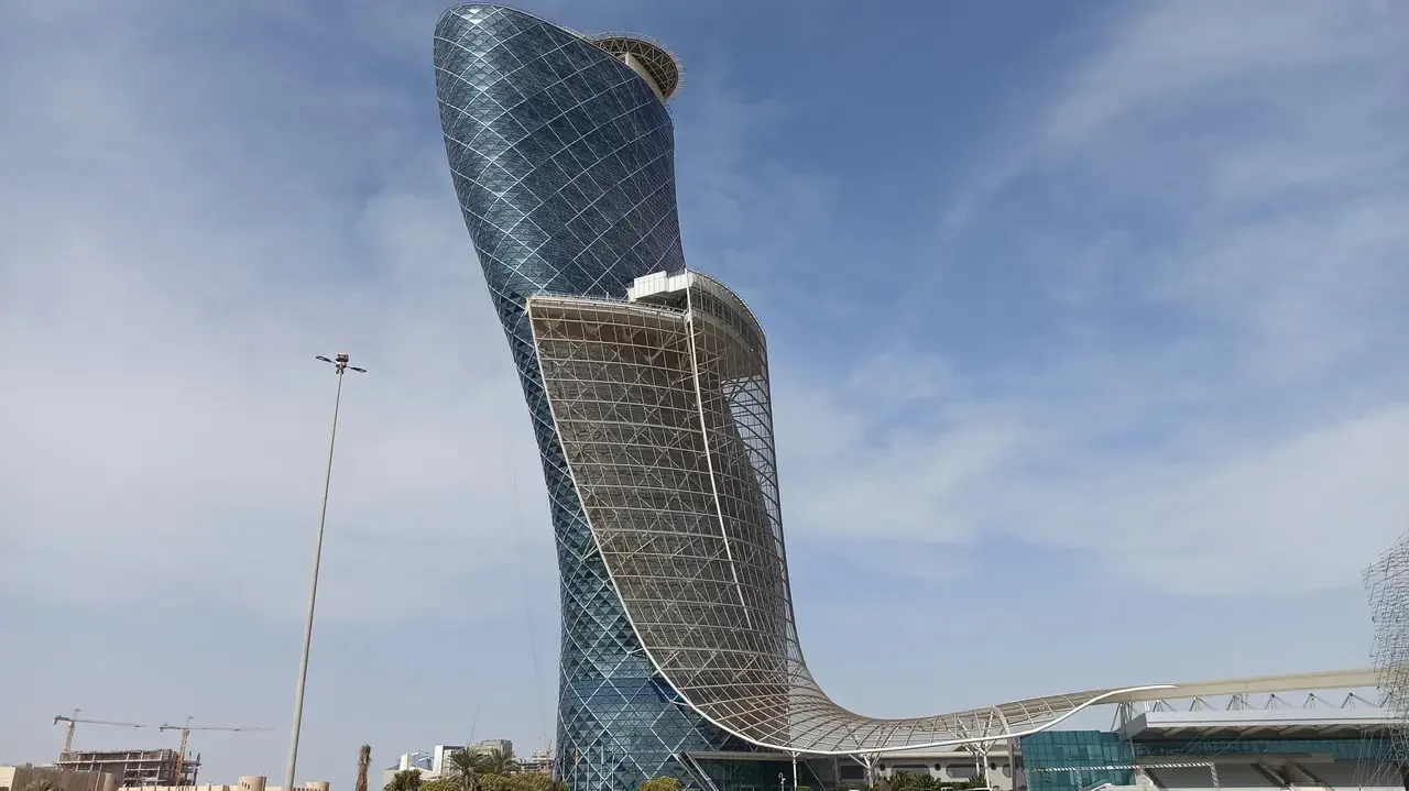 L'ingresso della capitale degli Emirati Arabi Uniti mostra un edificio moderno e curvo sotto il cielo azzurro.