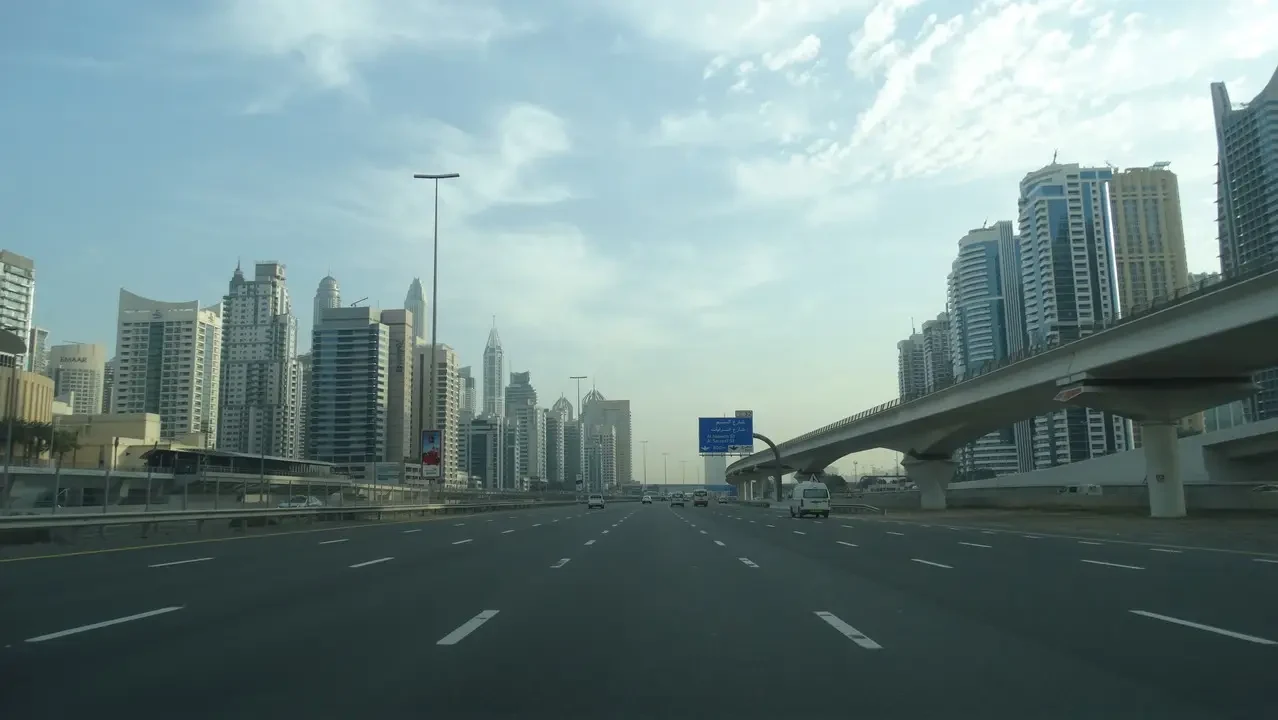 Paesaggio urbano con edifici moderni lungo una strada ampia in un contesto del Golfo.