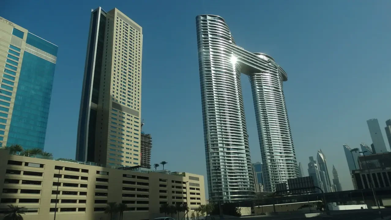 Grattacieli moderni dominano il panorama urbano di Dubai con uno sfondo che evoca l'Oman e gli Emirati Arabi Uniti.