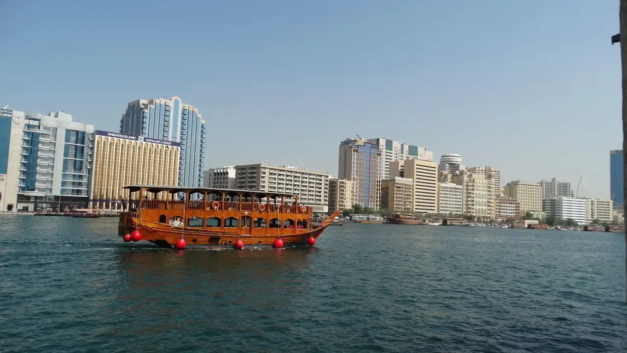 Un battello tradizionale naviga attraverso una città costiera in Oman o negli Emirati Arabi Uniti.