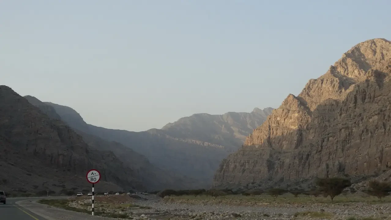 Una strada panoramica attraversa un paesaggio montano arido in Oman o negli Emirati Arabi Uniti.