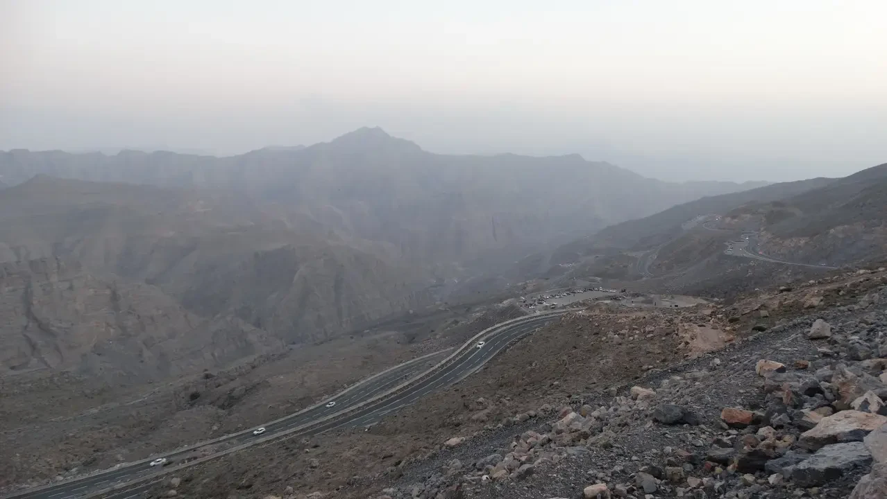 Paesaggio montuoso e desertico con una strada che serpeggia attraverso le valli.