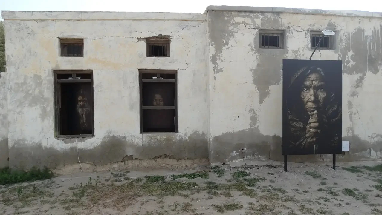 Facciata di un edificio in pietra con finestre vuote e un'opera d'arte murale.
