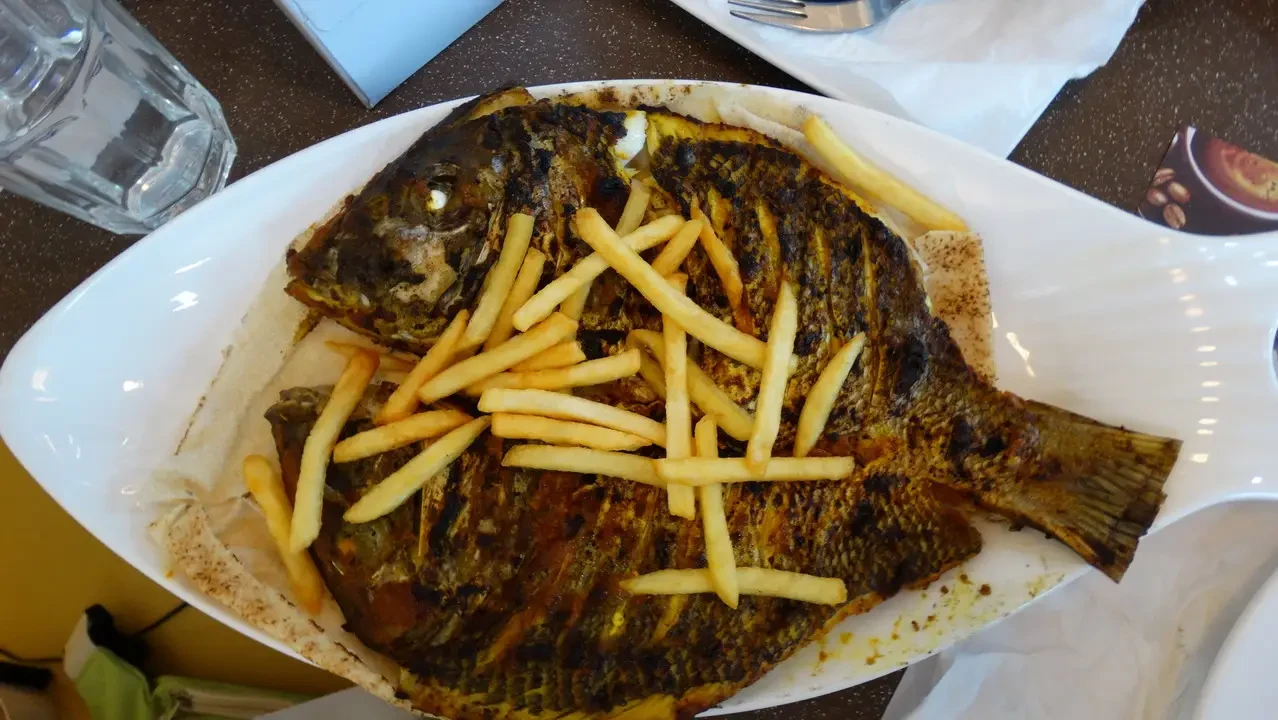 Pesce al forno con patate fritte su un tavolo in stile Omani o emiratese.