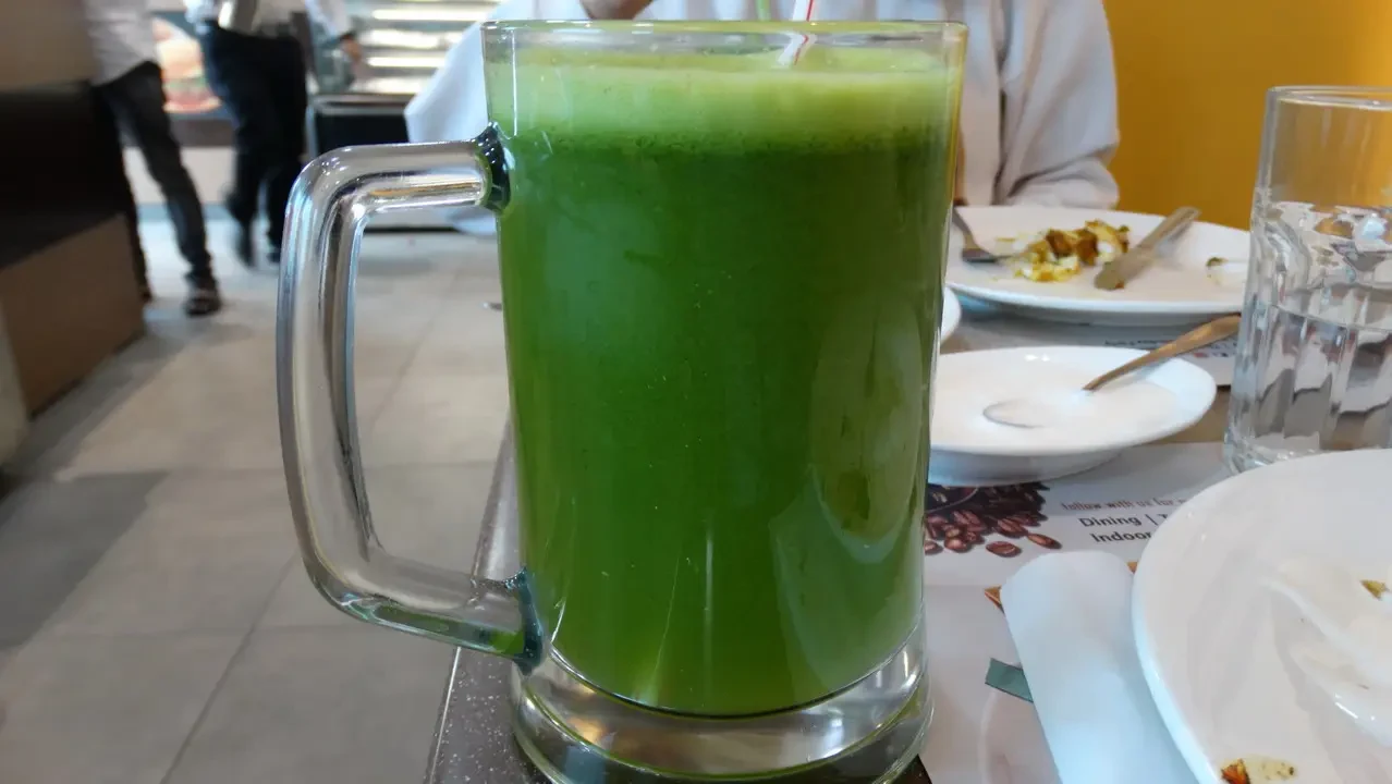 Un bicchiere di succo verde viene servito in un ambiente interno.