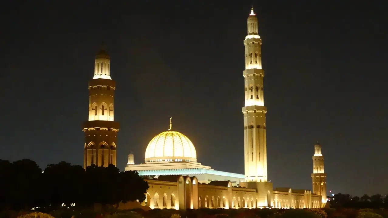 Grande Moschea del Sultano Qaboos illuminata di notte a Muscat.