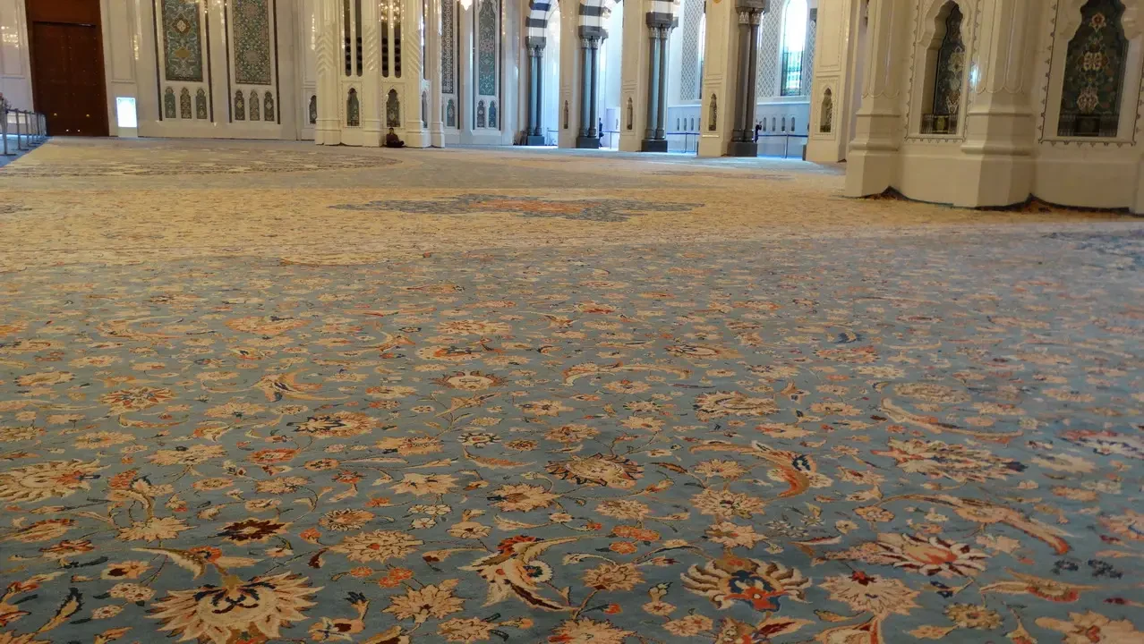 Interno sontuoso di un edificio con pavimenti decorati in motivi intricati.