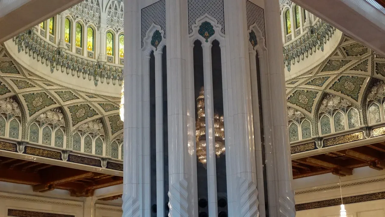 Interni sontuosi di una grande moschea con soffitti e colonne riccamente decorati.