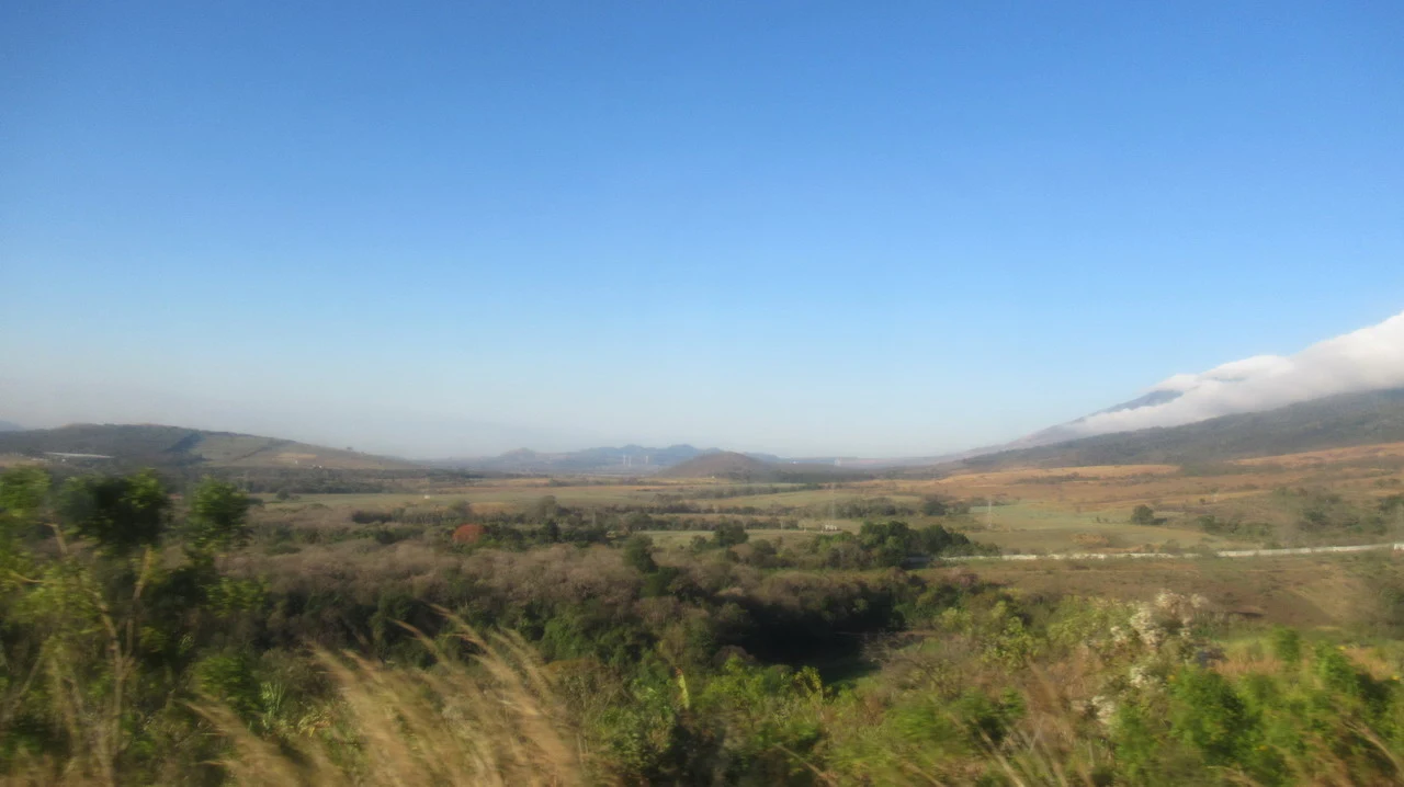 Paesaggio rurale che mostra un vasto panorama collinare sotto un cielo azzurro.