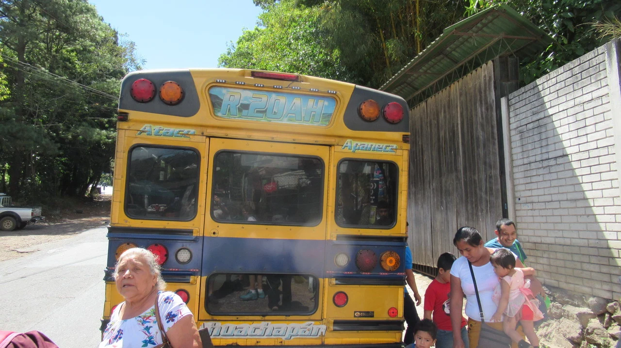 Un autobus giallo attraversa una strada rurale in America Centrale.