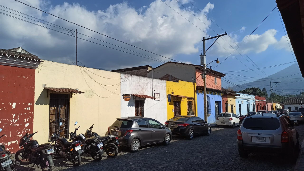 Una strada in pietra con edifici colorati e veicoli parcheggiati in America Centrale.