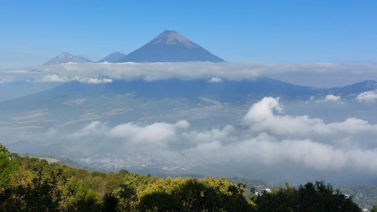 Vista panoramica del vulcano Pacaya-Volcán sopra un paesaggio avvolto dalle nuvole.
