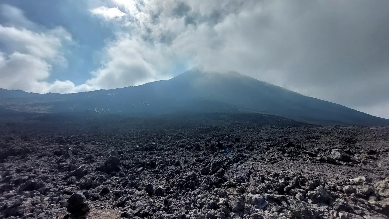 Il vulcano Pacaya si erge sopra un paesaggio roccioso sotto nuvole basse.