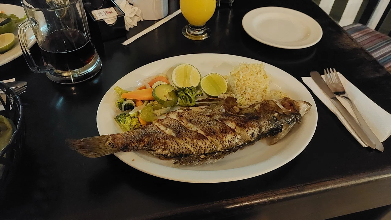 Pesce al forno con contorno di verdure e lime in un contesto da cena.